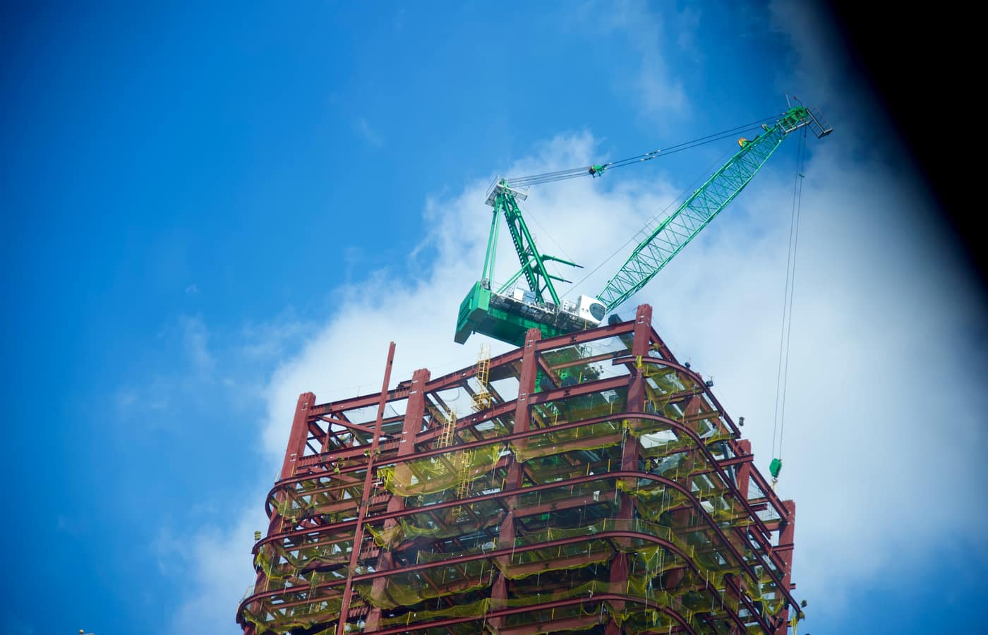 A steel-frame commercial building under construction with a tower crane