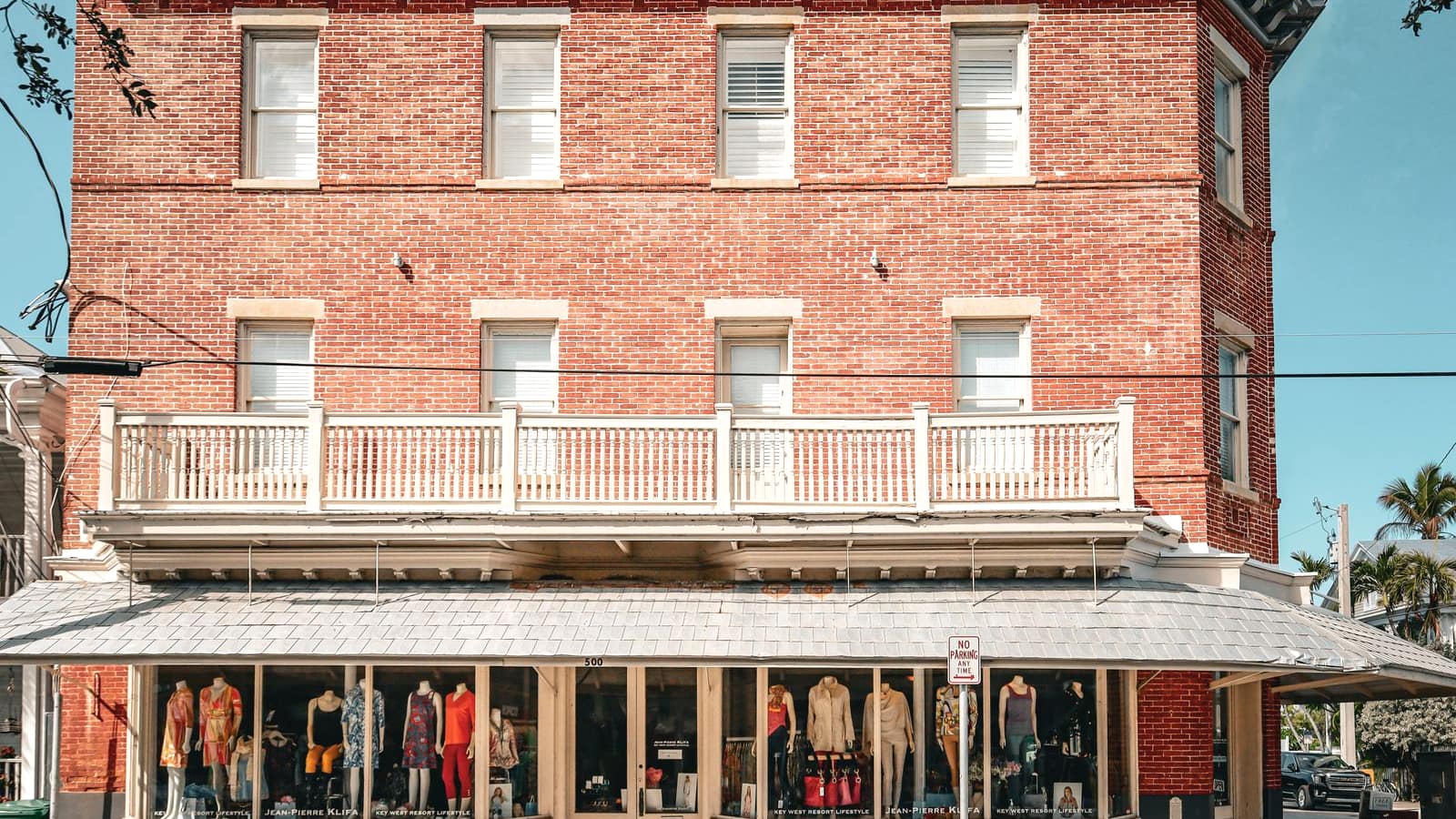 A three-story red brick commercial building with a ground-floor storefront
