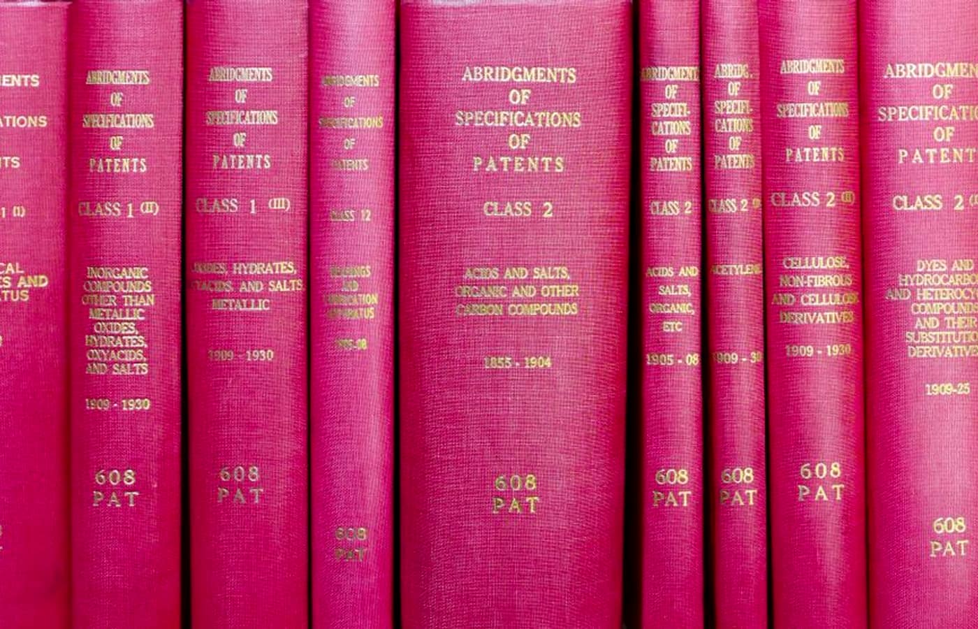 A row of bound red patent-abridgment reference volumes on a library shelf.